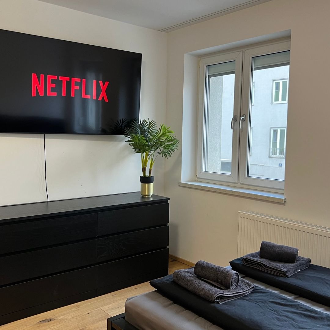 Modernes Schlafzimmer mit Smart-TV und frischer Wäsche